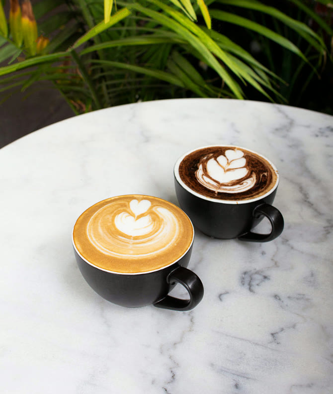 Dos lattes con arte en la espuma sobre una mesa de mármol