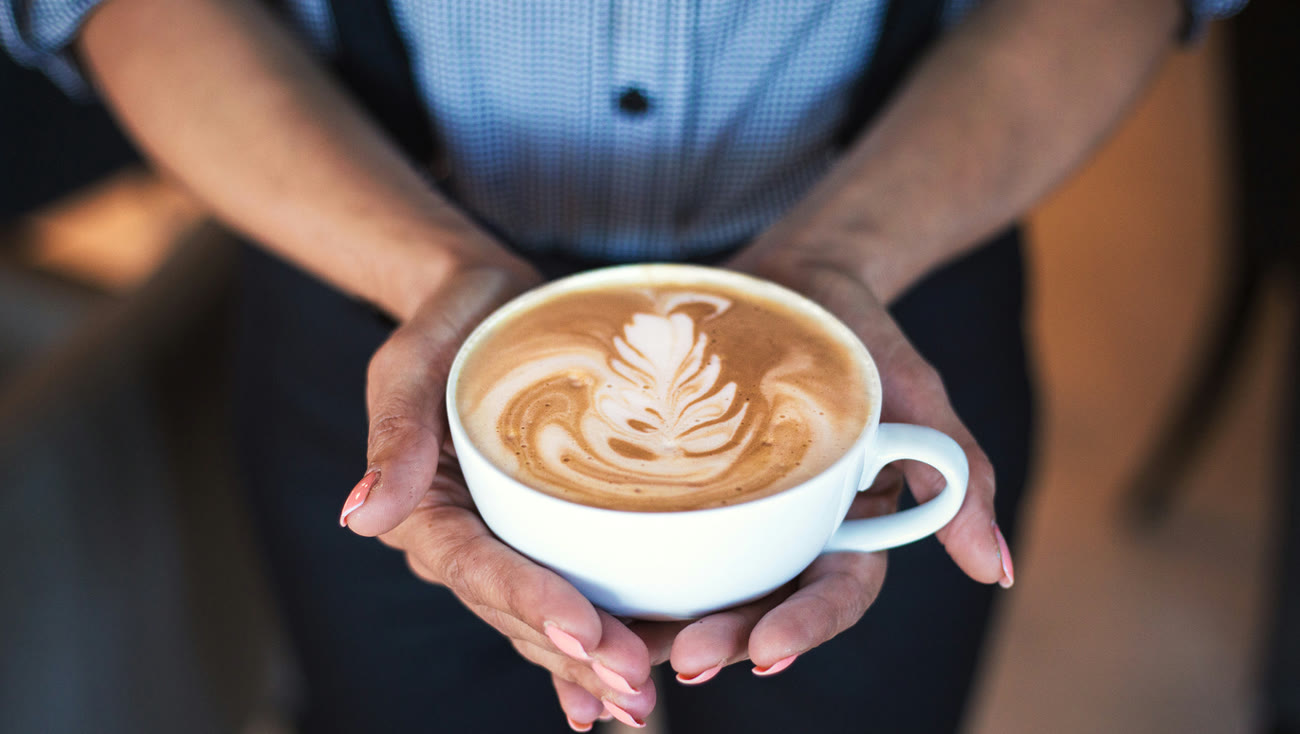Barista ofreciendo un cappuccino con latte art
